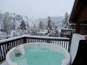 Hot tub on deck in the winter at with snow covered forest in background at Three Rivers Resort and Outfitting property in Almont north of Gunnison Colorado. Riverfront Cabins, Lodge Rooms, Vacation Home.