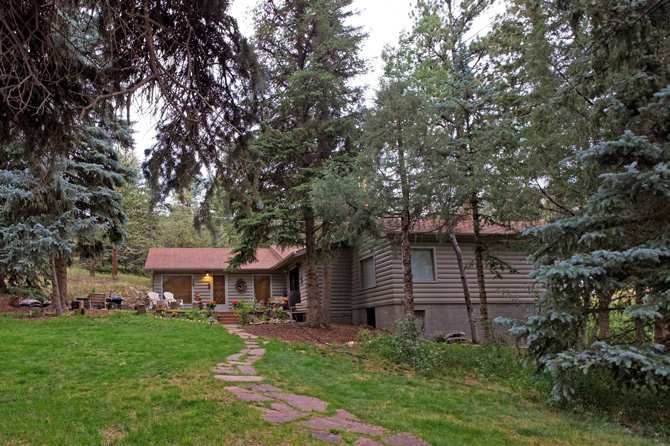 Shaded pathway to log cabin at Bear Paw Cabins in Estes Park, Colorado.