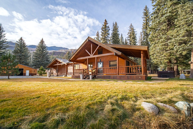 View of cabin with front porch deck and park bench during the fall at Bear Paw Lodge, Cabins, and Vacation Homes in Durango, Colorado.