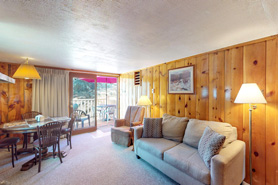 View of living area inside log cabin with tv, loft and fireplace at Blackhawk Cabins in Estes Park, Colorado.