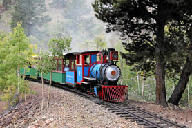 Scenic steam locomotive train ride going through aspens and pine trees at Cripple Creek and Victor Narrow Gauge Railroad in Cripple Creek, Colorado.