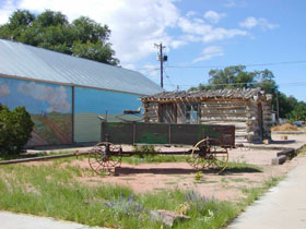 Historic antique horse wagon and log cabin in downtown Fowler, Colorado.
