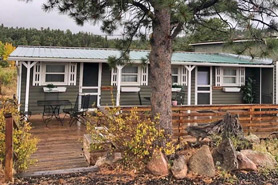 Exterior view of Cabin Triplex with large deck, table and chairs at Hill Top General Store, Cabins and Antiques in Red Feather Lakes, Colorado.