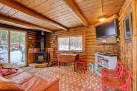 Inside view of cozy cabin with kitchen, dining table, couch, internet tv and wood-stove at Honeymoon Hideout Cabin among trees located in Allenspark near Lyons and Estes Park, Colorado.