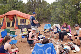 Family sitting around a campfire at a tent camping site at Indian Springs Ranch and Campground in the Royal Gorge area of Colorado.