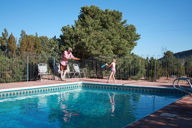 Family having water-gun battle next to outdoor swimming pool at Indian Springs Ranch and Campground in the Royal Gorge area of Colorado.