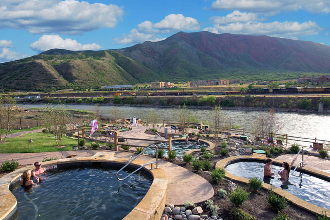 People relaxing in hot springs pools overlooking the Colorado River at Iron Mountain Hot Springs in Glenwood Springs, Colorado.